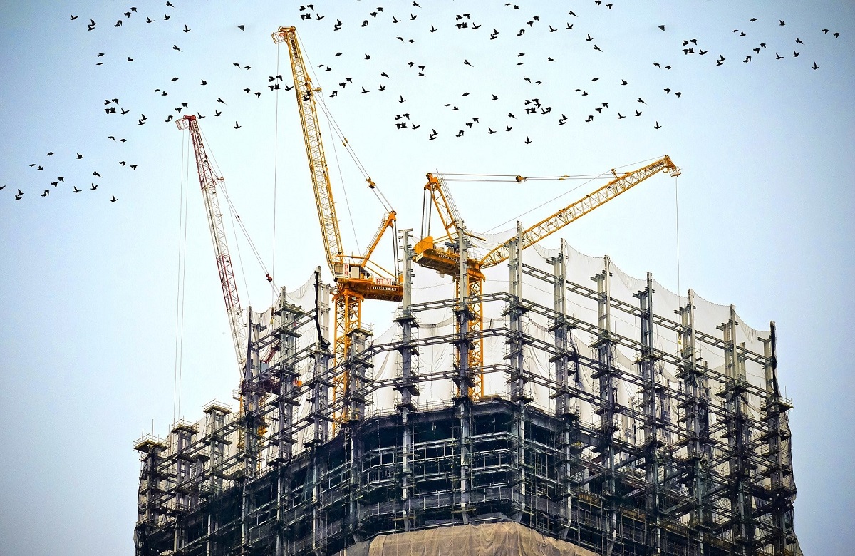 A construction site with equipment and birds in the sky