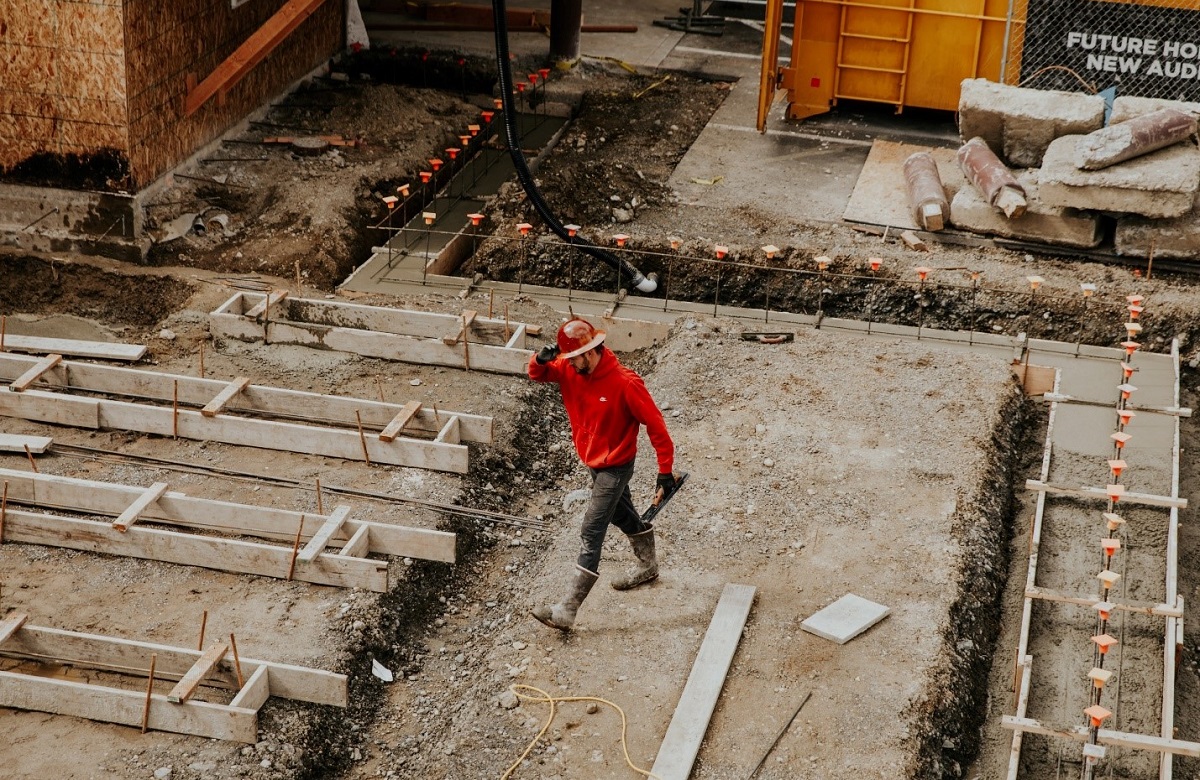 A man at a construction site holding a concrete leveling tool